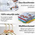 Cederhouten balletjes in witte sportschoenen, gestapelde kleding en cederhouten ringen op kledinghangers.