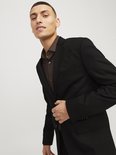 Man in zwart JACK & JONES blazer met bruine blouse. Hij draagt de blazer open en legt zijn hand op de revers.