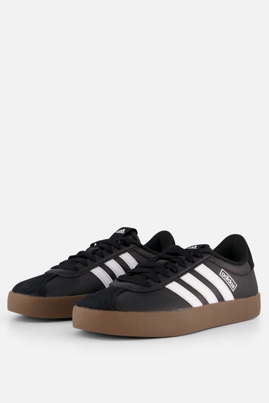 Baskets Adidas noires et cuir avec bandes blanches et semelle marron.