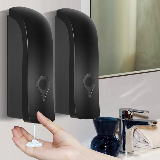 Twee zwarte zeepdispensers aan de muur, een hand wordt onder de dispenser gehouden om zeep op te vangen.