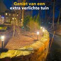 Donker tuinpad verlicht door meerdere solar fakkels langs een stenen muur.