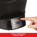 Vinger drukt op de digitale bedieningspaneel van een zwarte Russell Hobbs multicooker.