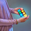 Meisje met paarse trui speelt met een Flipslide spel met rode, gele, groene en blauwe blokjes die oplichten.
