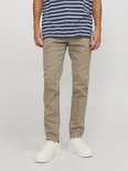 Man in gestreept t-shirt en beige chino broek, staand op een lichte achtergrond.