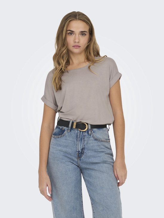 Model met een lichtbruine top met omgeslagen korte mouwen en een zwarte riem met gouden gesp.