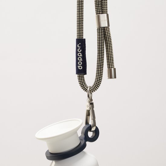 Dopper koord met gesp aan de bovenkant, een zwarte lus en een metalen clip. Het koord heeft een zwart-wit ruitpatroon.