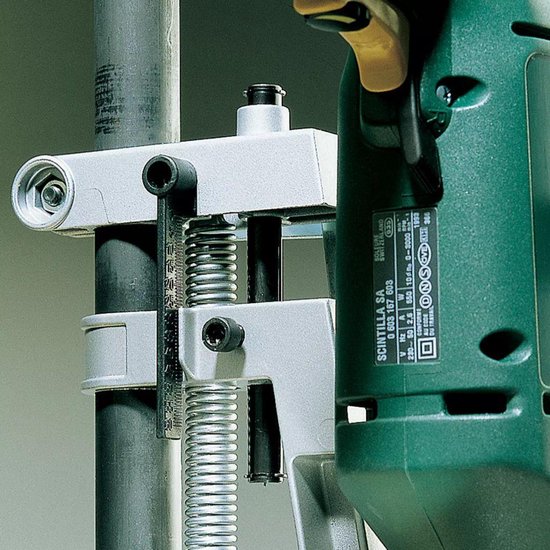 Detailopname van een boorstandaard met groene boormachine, close-up van de klemmechanisme.