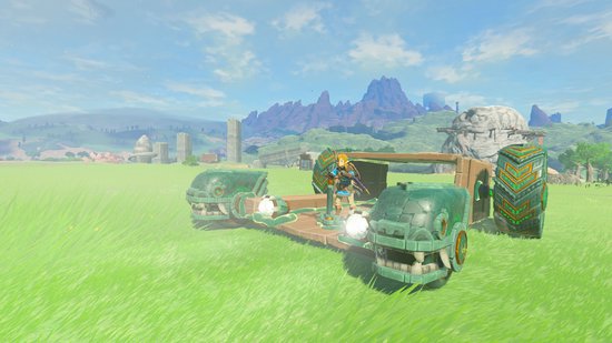 Link staat op een houten constructie met twee stenen 'hoofdwielen' en twee grote wielen, in een groen grasveld.