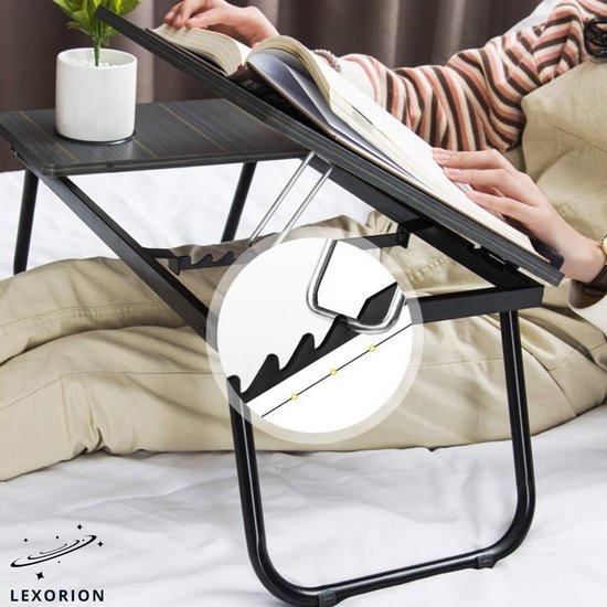 Dichtbij van een verstelbare, kantelbare laptoptafel met een boek en een kleine plant.