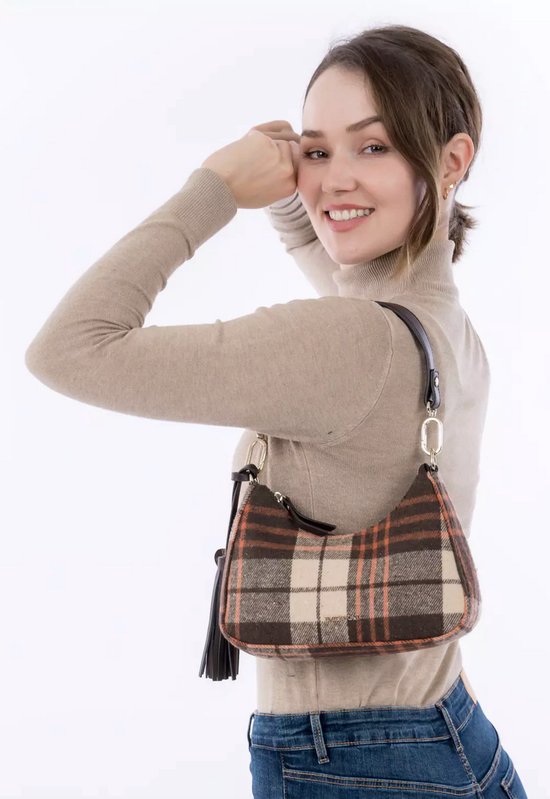 Model draagt bruine en beige ruitjes schoudertas met franjes over haar schouder.