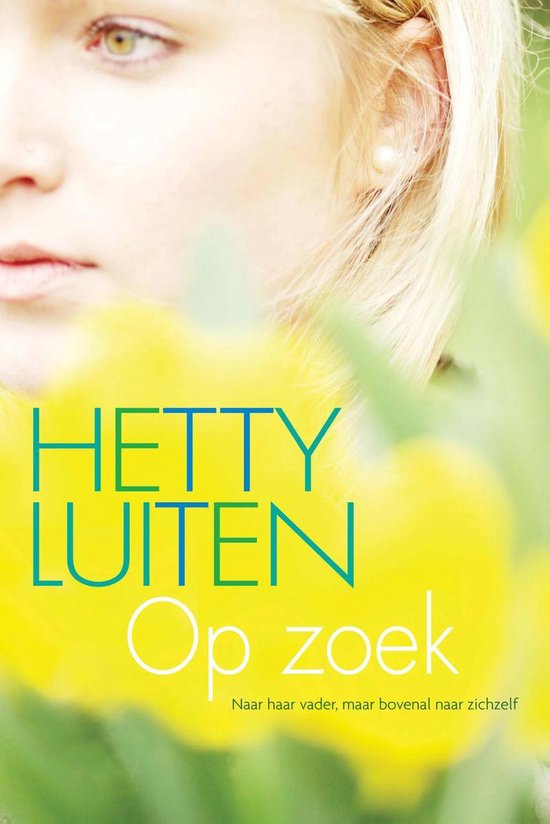 Close-up van een jonge vrouw met blond haar, gericht op haar gezicht. De tekst 'Hetty Luiten Op zoek' staat voor gele bloemen.