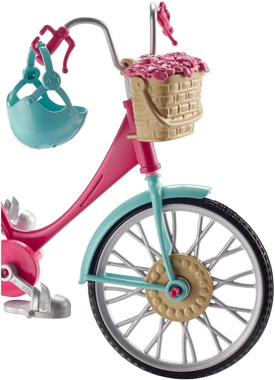 Roze Barbie fiets met lichtblauwe spatborden, rieten mandje met bloemen en blauwe helm aan stuur.