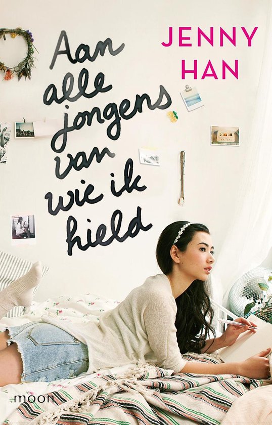 Fille sur un lit avec un carnet et un stylo, devant un mur avec le texte 'À tous les garçons que j'ai aimés'.
