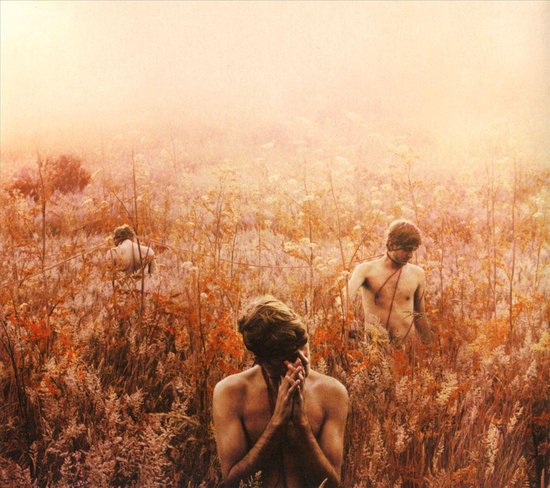 Trois hommes avec des cordes autour de la taille, debout dans un champ d'herbes sèches et de feuilles d'automne.
