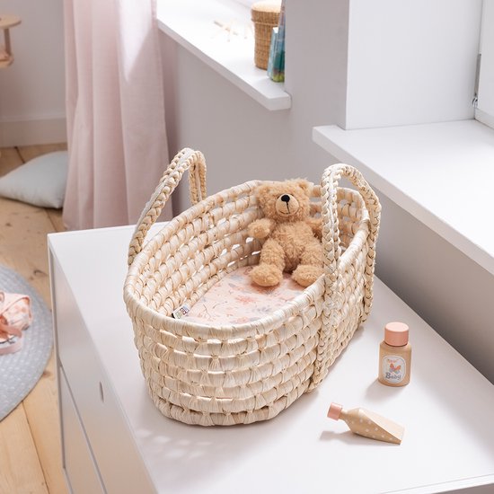 Hoea poppendrager van zeegras met een roze bloemenmatras, teddybeer en babyverzorgingsproducten.