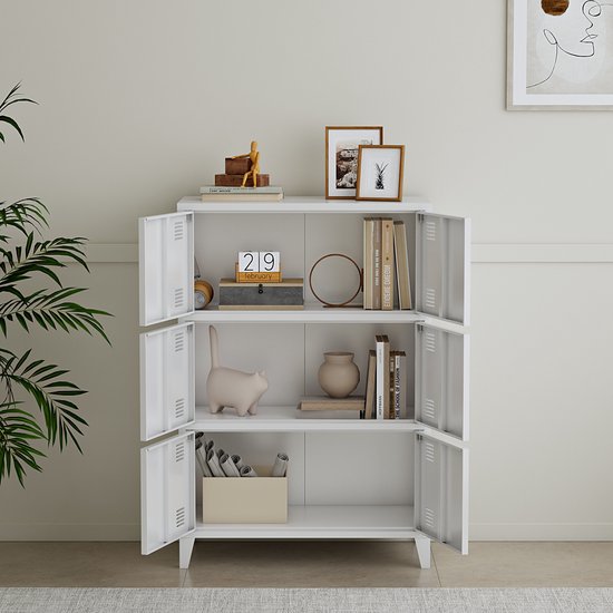 Witte kast in een kamer, met decoratie: boeken, vaas, katbeeldje en plant.