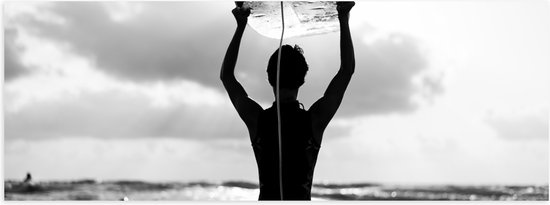 Poster Glanzend – Achteraanzicht van Persoon met Surfplank boven het Hoofd (Zwart-wit) - 60x20 cm Foto op Posterpapier met Glanzende Afwerking