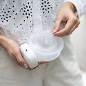 Vrouw houdt witte borstkolf met 26mm borstschildverkleiner vast. De verkleiner is doorzichtig.