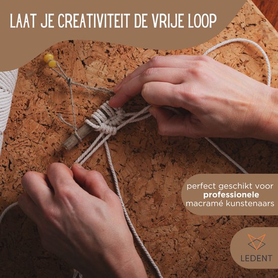 Handen maken een macraméknoop met lichtgrijs touw om een stokje, op een kurken ondergrond.