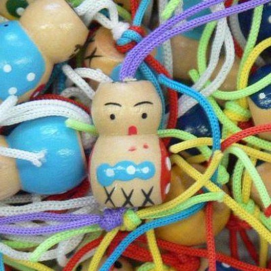 Houten gelukspoppetjes met gekleurde koordjes, met gezichtjes en XXX op buik.