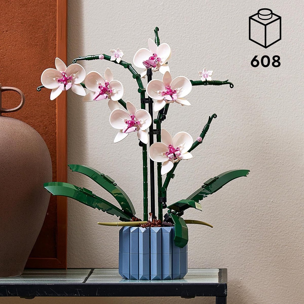 Set voor volwassenen bestaat uit een orchidee plant met witte en roze bloemblaadjes en een blauwe geribbelde vaas