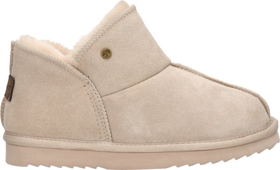 Beige suède pantoffel met beige teddy voering en een bruin label met Warmbat logo aan de zijkant.
