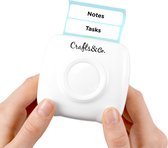 Witte Crafts&Co mini printer met twee uitstekende labels, tekst 'Notes' en 'Tasks', vastgehouden door handen.