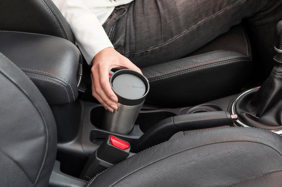 Vrouw plaatst een roestvrijstalen thermosbeker met grijs deksel in de bekerhouder van een auto.