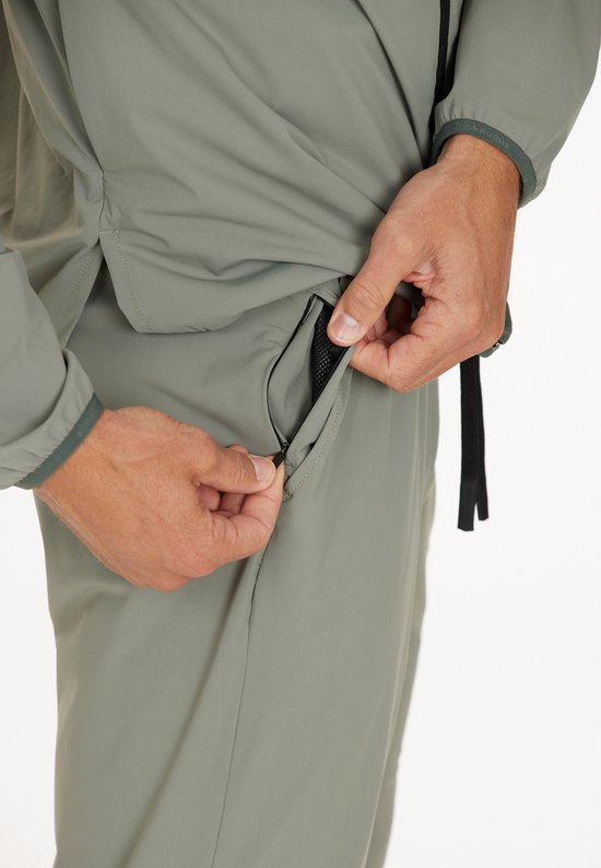 Grijze sportbroek met ritszak, gedragen door een man.