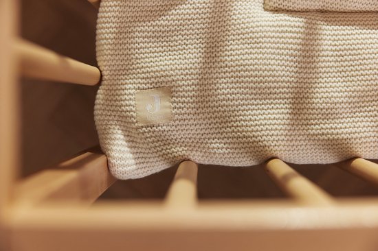 Couverture bébé en maille crème avec étiquette Jollein, dans un berceau.