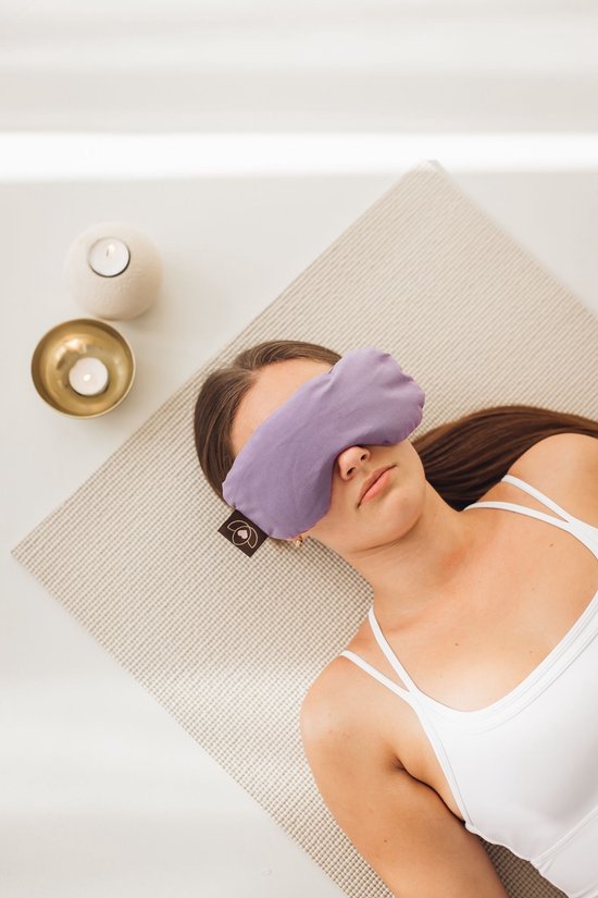 Femme allongée avec un masque pour les yeux violet sur les yeux, vue de dessus.