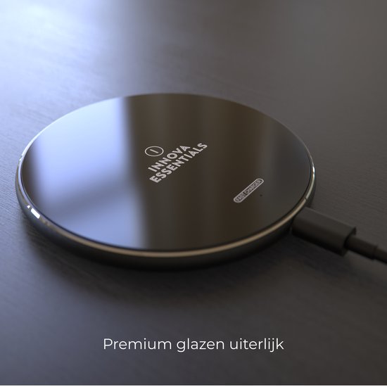 Zwarte ronde draadloze oplader met een glanzend oppervlak, op een donkere ondergrond. "Innova Essentials Fast Charger".