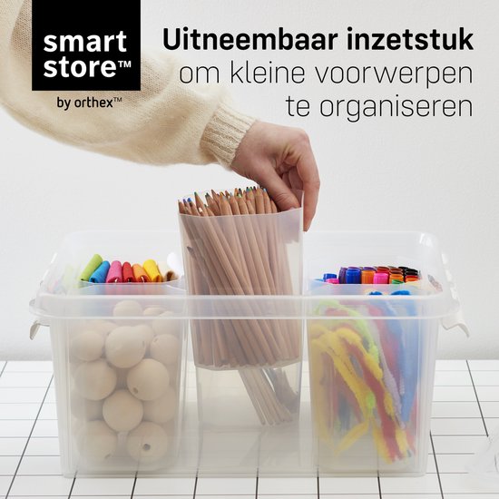 Transparante opbergdoos met vakverdelers, gevuld met potloden, bollen, pijpenreinigers en stiften.