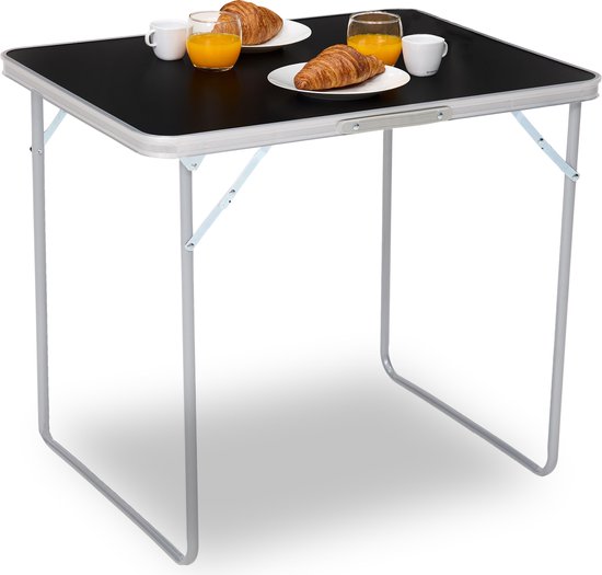 Zwarte tafel met aluminium frame, gedekt met twee croissants en jus d'orange.