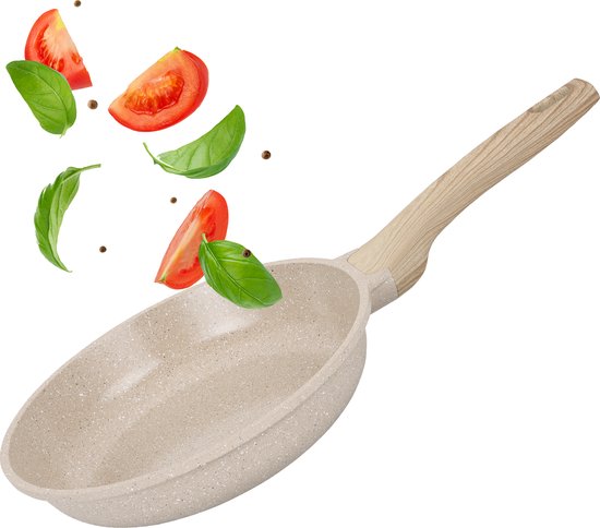 Beige koekenpan met licht houten handvat. Tomatenpartjes en basilicumblaadjes zweven erboven.