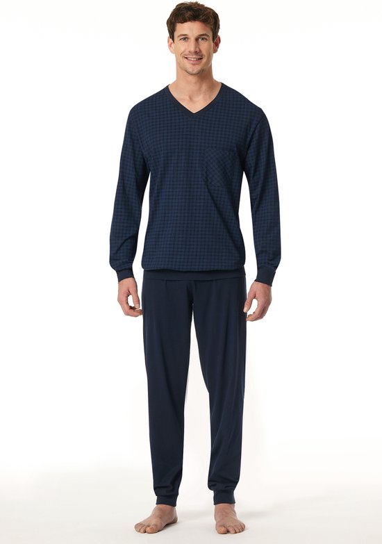 Man staand in een donkerblauwe pyjamaset met ruitpatroon.
