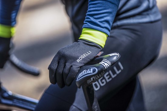 Zwarte Rogelli fietshandschoen met stippenpatroon op de handpalm, rustend op een fietszadel.