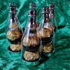 Quatre bouteilles avec bouchons argentés, chacune remplie de pralines Ferrero Rocher en papier doré.