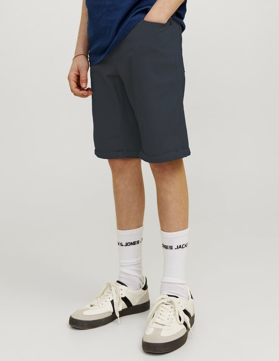 Garçon en short bleu marine et chaussettes blanches avec logo, debout.
