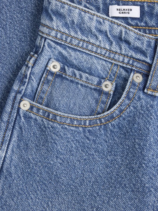 Detail van de spijkerbroek met het label 'RELAXED CHRIS'.