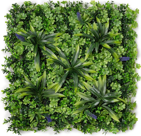 Groene plantenmuur met buxus, tropische planten en paarse bloemetjes.