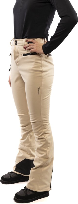 Vrouw in beige skibroek met zwarte accenten, zwarte schoenen en een zwarte top.