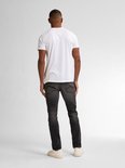 Man met rug naar de camera, draagt een witte t-shirt en zwarte slim fit jeans met vintage wassing.