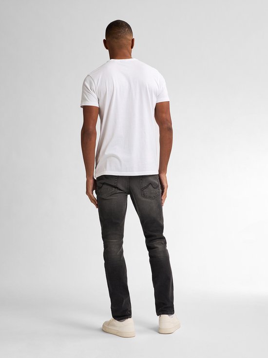 Man met rug naar de camera, draagt een witte t-shirt en zwarte slim fit jeans met vintage wassing.
