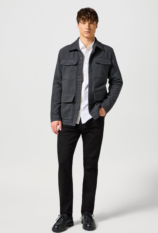Man met een zwarte Wrangler jeans, wit overhemd en grijs jack met vier zakken.