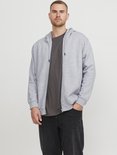 Man draagt een lichtgrijs vest met rits en capuchon over een donkergrijs T-shirt en een zwarte jeans.
