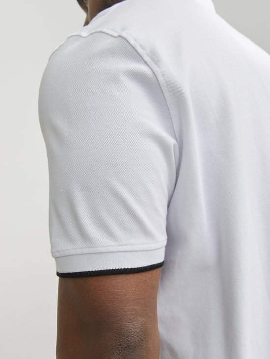 Close-up van de mouw van een lichtgrijze poloshirt met zwarte bies.