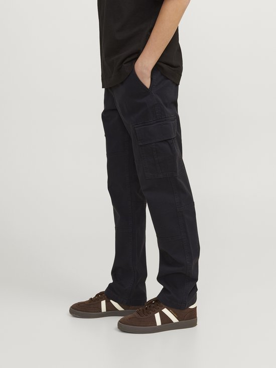 Jongen draagt een donkerblauwe cargo broek met zijzakken, zittend, hand in zak.