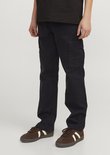 Donkerblauwe cargobroek met opgestikte zakken en bruine sneakers.