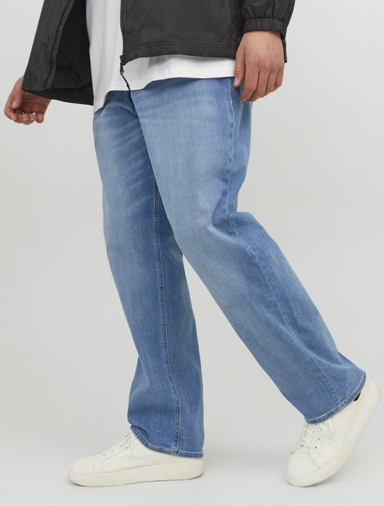 Man in een zwarte jas en blauwe jeans, die loopt.